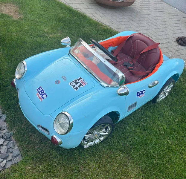 Mėlynas vaikiškas elektrinis automobilis ant žolės